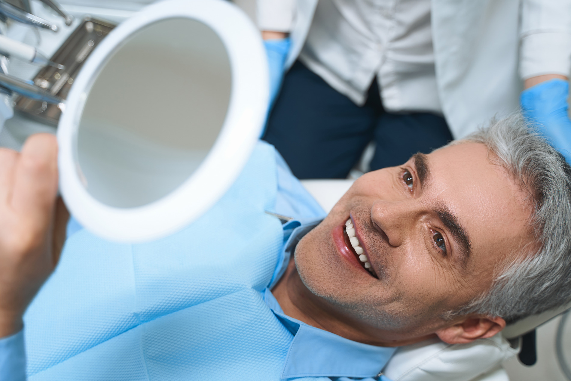 Happy man looking at his new veneers in Chesterfield MO